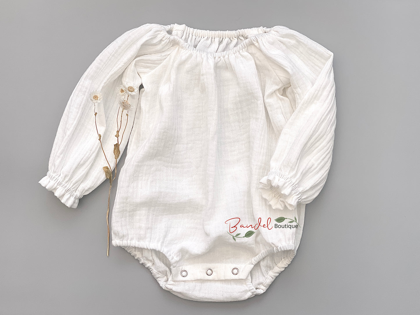 Handmade white minimalist newborn baby romper with long sleeves, made from breathable and soft double gauze organic fabric. Features elasticized openings and crotch snaps for easy dressing and maximum comfort. 