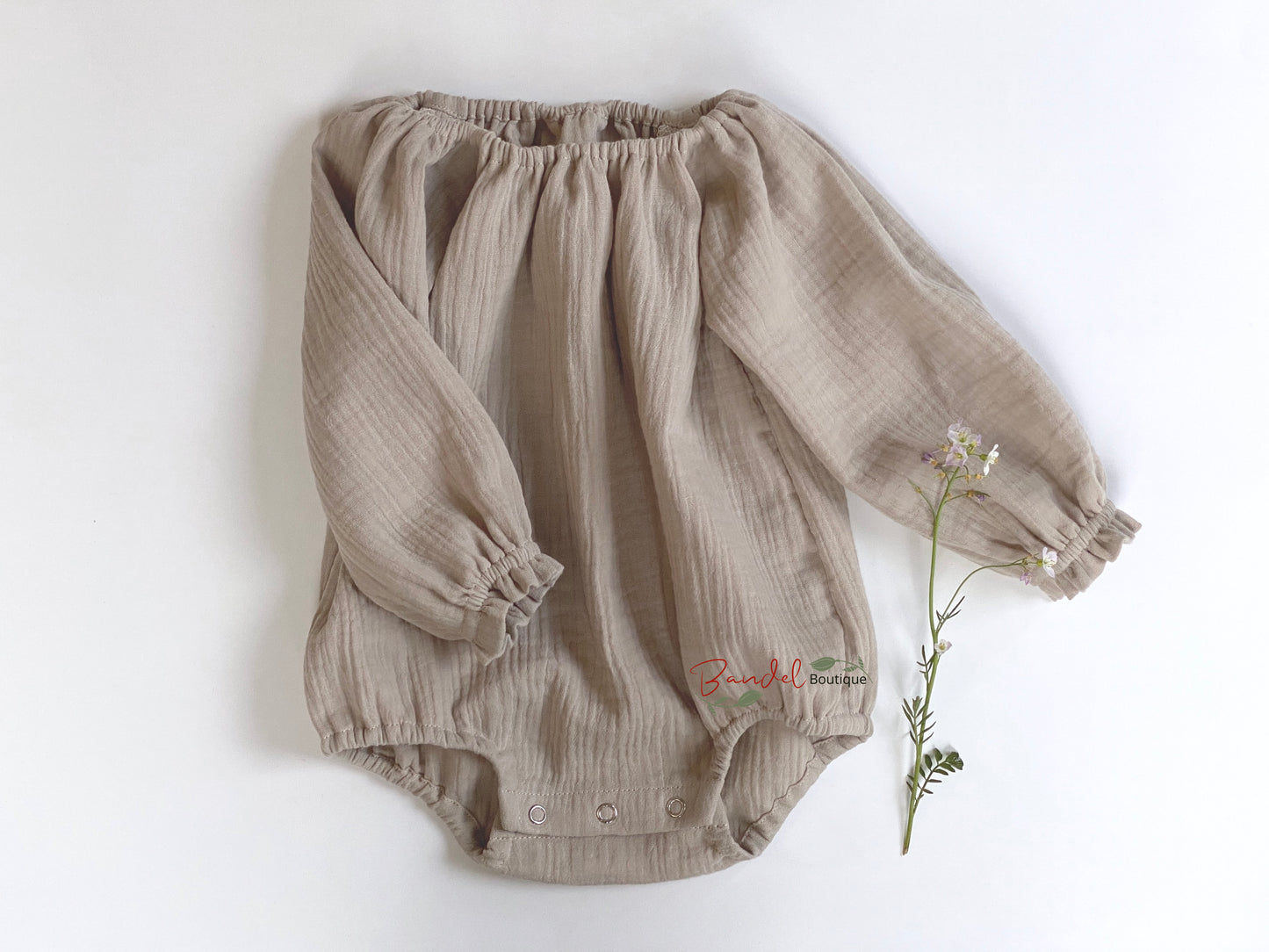 Handmade in The Netherlands sand- brown minimalist newborn baby romper with long sleeves, made from breathable and soft double gauze organic fabric. Features elasticized openings and crotch snaps for easy dressing and maximum comfort. 