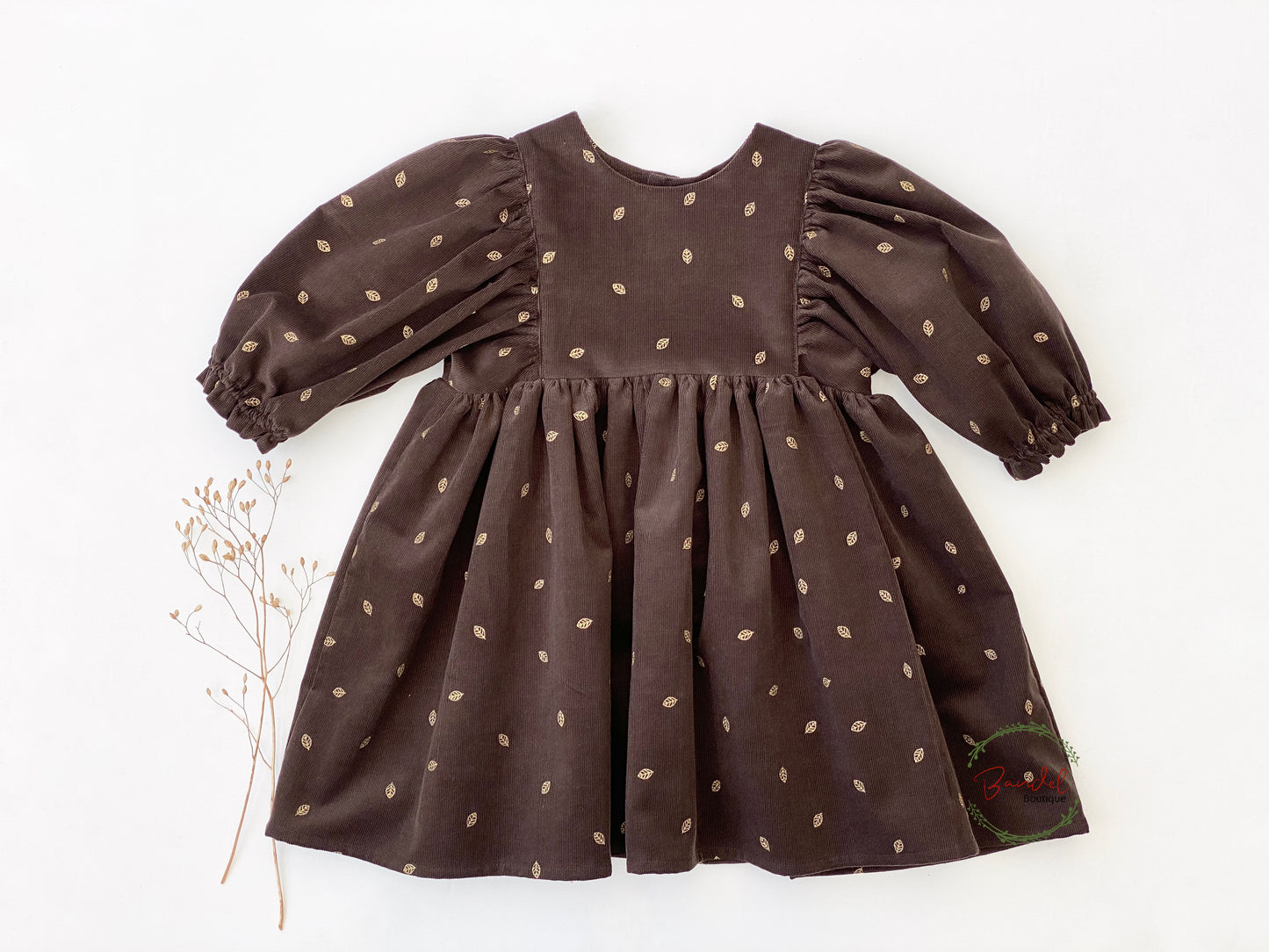 3/4 Sleeves Corduroy Girl Dress Crafted with a luxurious corduroy fabric featuring gold leafs prints and classic styling, this whimsical dress is finished with a ruffled hem, 3/4 length sleeves, and a wooden button closure at the back bodice.