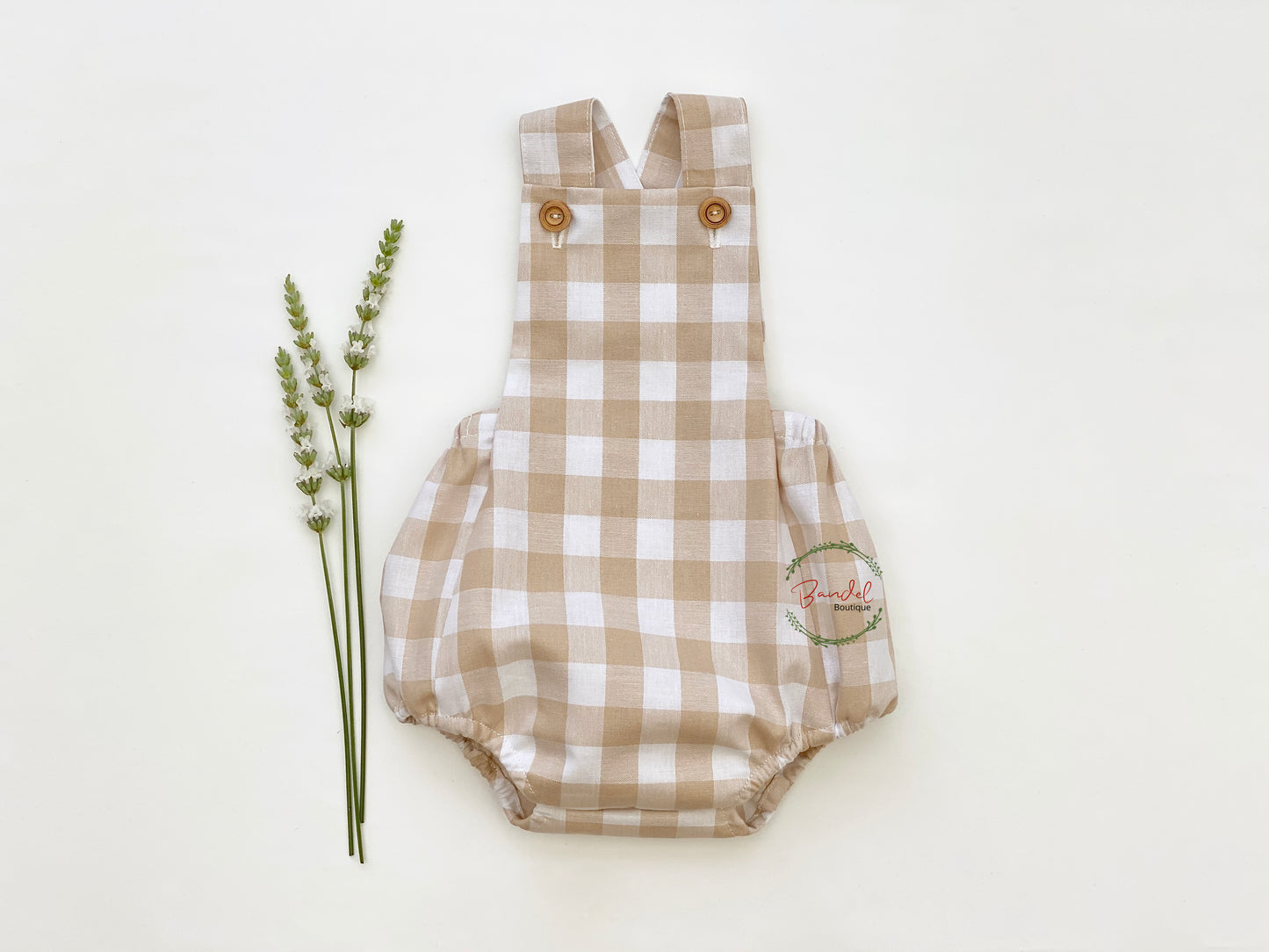 Cream Gingham Cotton Baby Romper. Crafted from breathable cotton fabric in an easy-to-care-for cream check pattern, it features two shoulder straps to keep them secure and a convenient front wooden button closure for easy dressing.