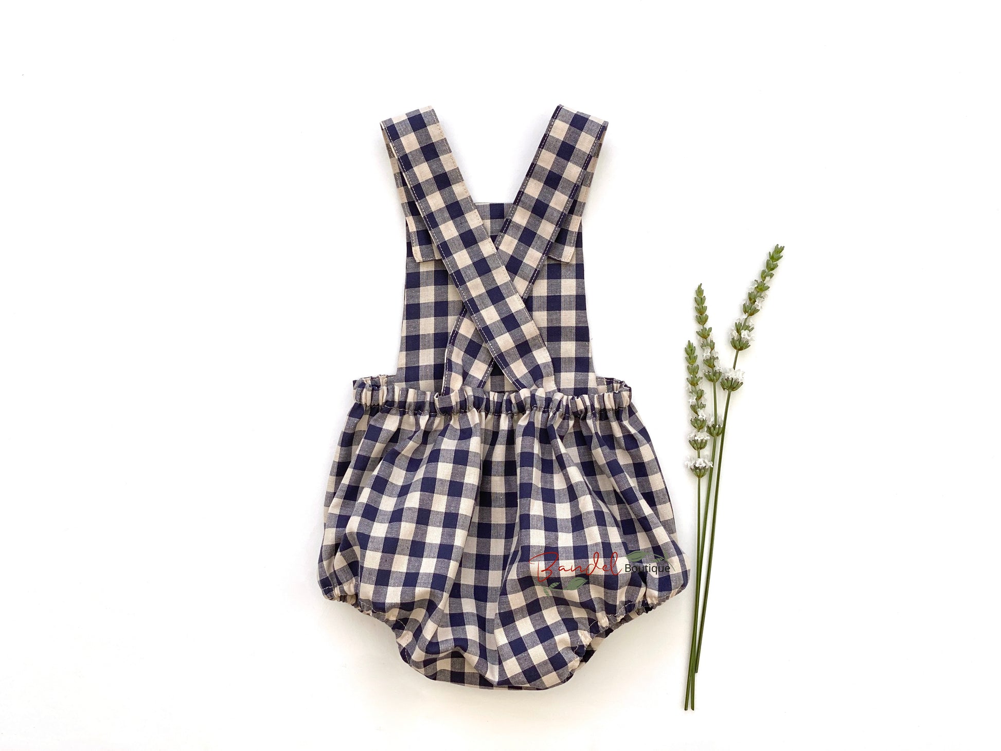 Adorable blue gingham baby romper featuring adjustable straps and rustic wooden buttons.