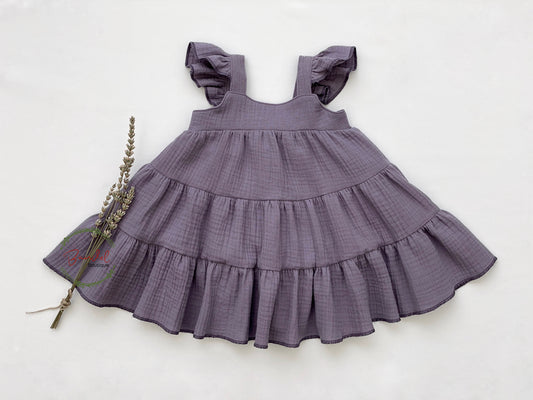 Lilac Flutter Sleeve Girl Dress is crafted from sustainable muslin fabric. It features a gathered tiered skirt, flutter sleeves, and an elastic back bodice for a perfect fit.