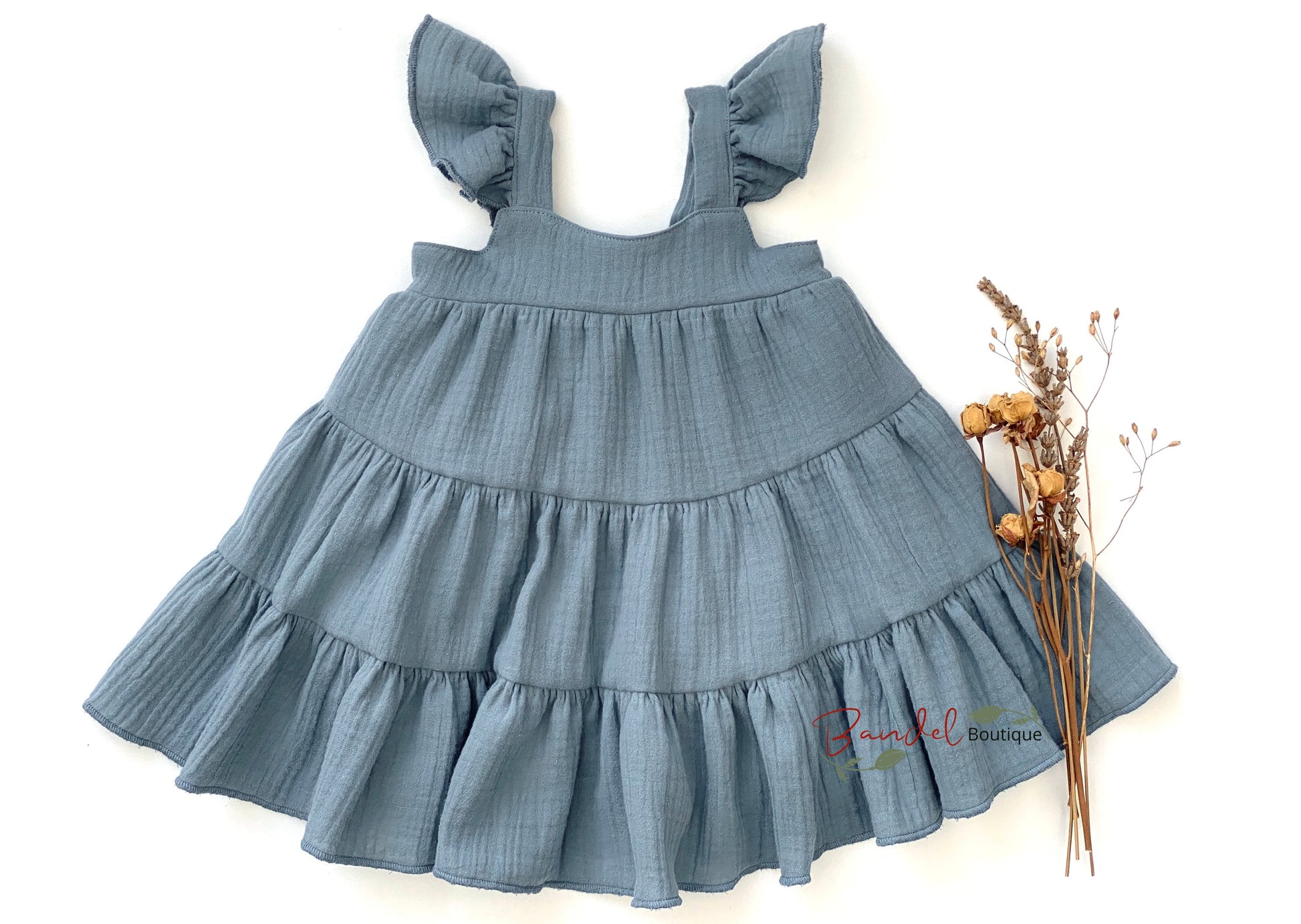 This timeless dress is perfect for your little girl. Carefully crafted from sustainable muslin, this Dusty- Blue dress features a gathered tier skirt, flutter sleeves and an elastic back bodice for easy dressing.