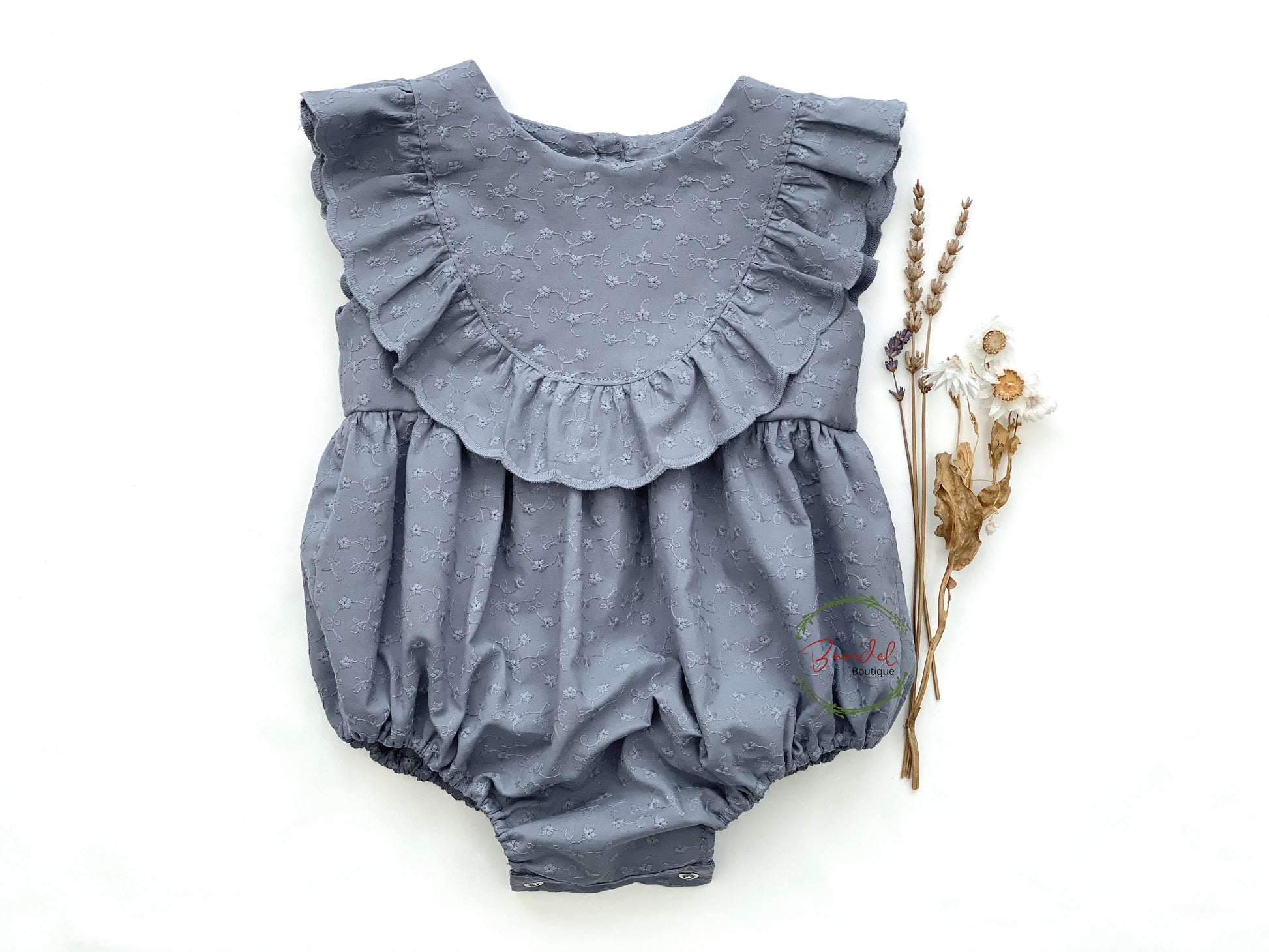 Dusty-Blue Romper is a perfect staple piece for any baby girl's wardrobe. Crafted with soft, breathable fabric, this romper features a delicate embroidery design and a ruffled front bodice. It also includes convenient snap closure at the crotch, making diaper changing and outfit adjustments effortless.