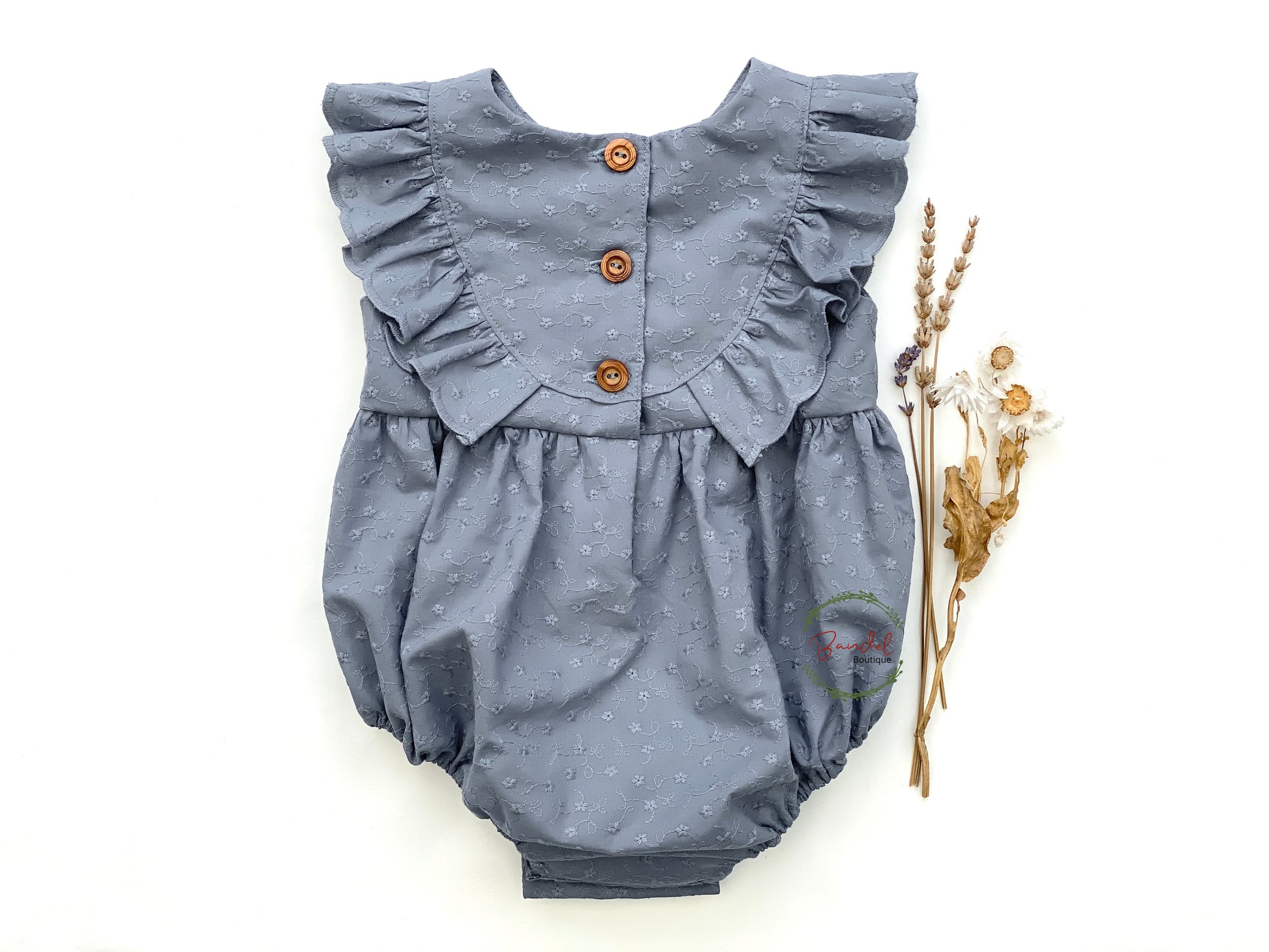 Dusty-Blue Romper is a perfect staple piece for any baby girl's wardrobe. Crafted with soft, breathable fabric, this romper features a delicate embroidery design and a ruffled front bodice. It also includes convenient snap closure at the crotch, making diaper changing and outfit adjustments effortless.