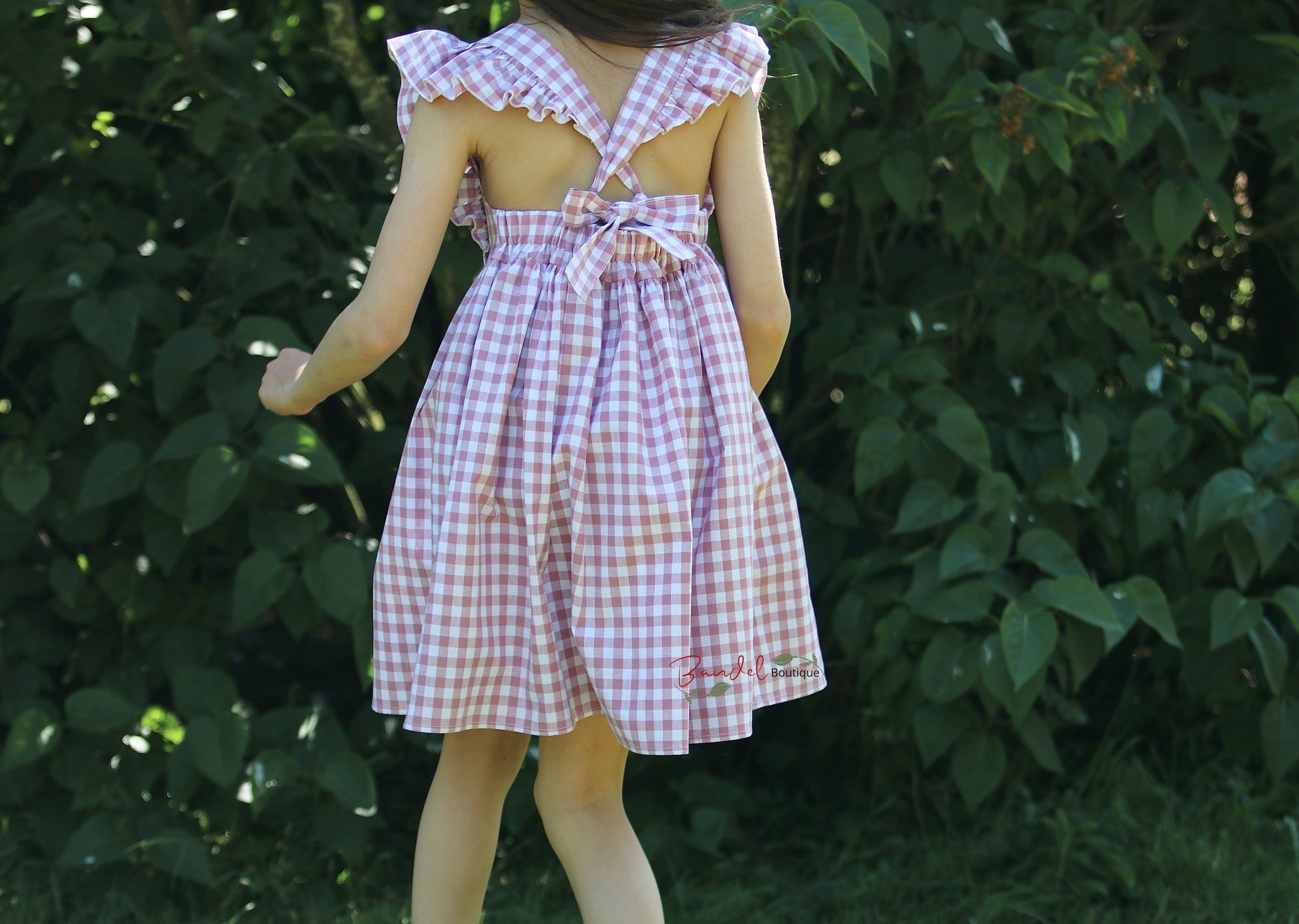 Vintage- inspired pinafore check  girl dress in old- rose color, features delightful sleeve ruffles, adjustable straps and gathered skirt. 