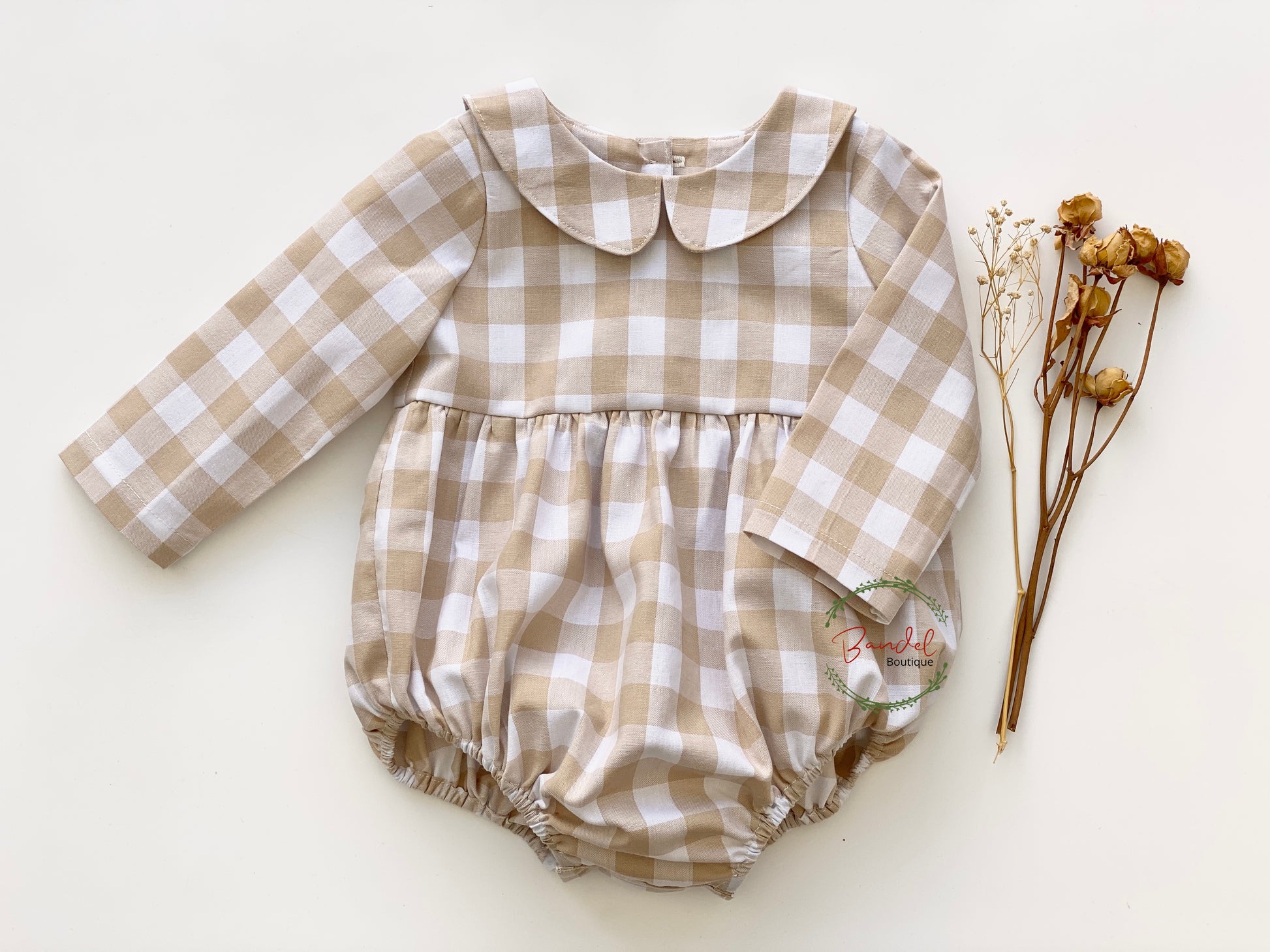 classic Cream Check Romper is lovingly handmade to offer lasting comfort and style for your little one. Crafted from beige check cotton, it features long-sleeves, a Peter Pan collar, elastic at the leg, wooden buttons at the back and snaps at the crotch for easy dressing.