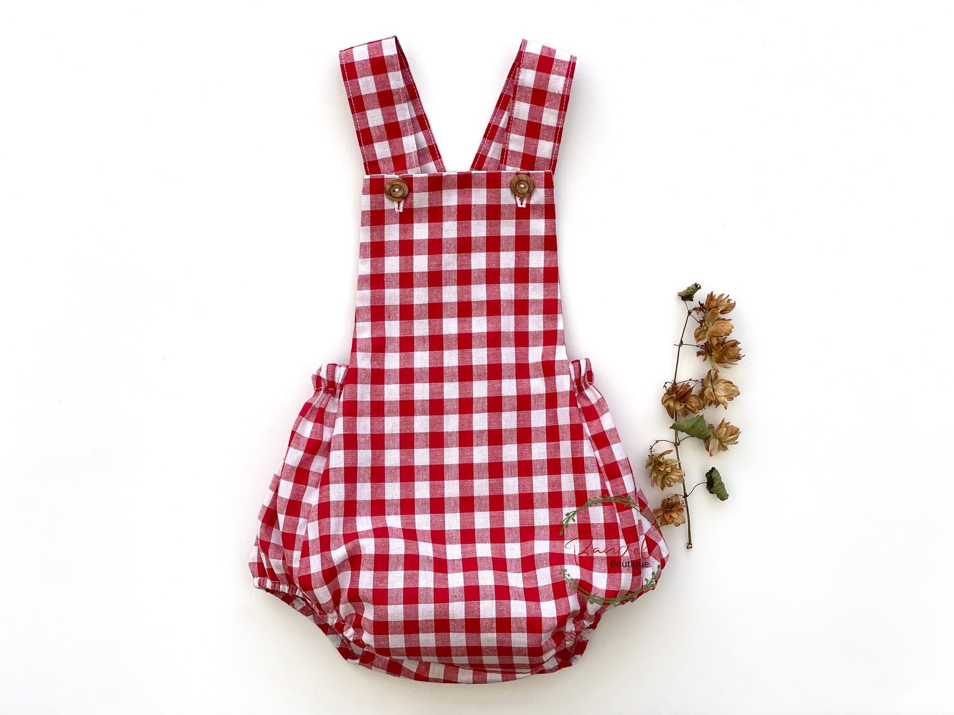 Stay comfortable and stylish this holiday season in our Red Check Cotton Baby Romper. This piece features shoulder straps with front wooden button closure, an elastic back waistband, and leg openings to ensure a great fit. Be festive and look your best this holiday season.